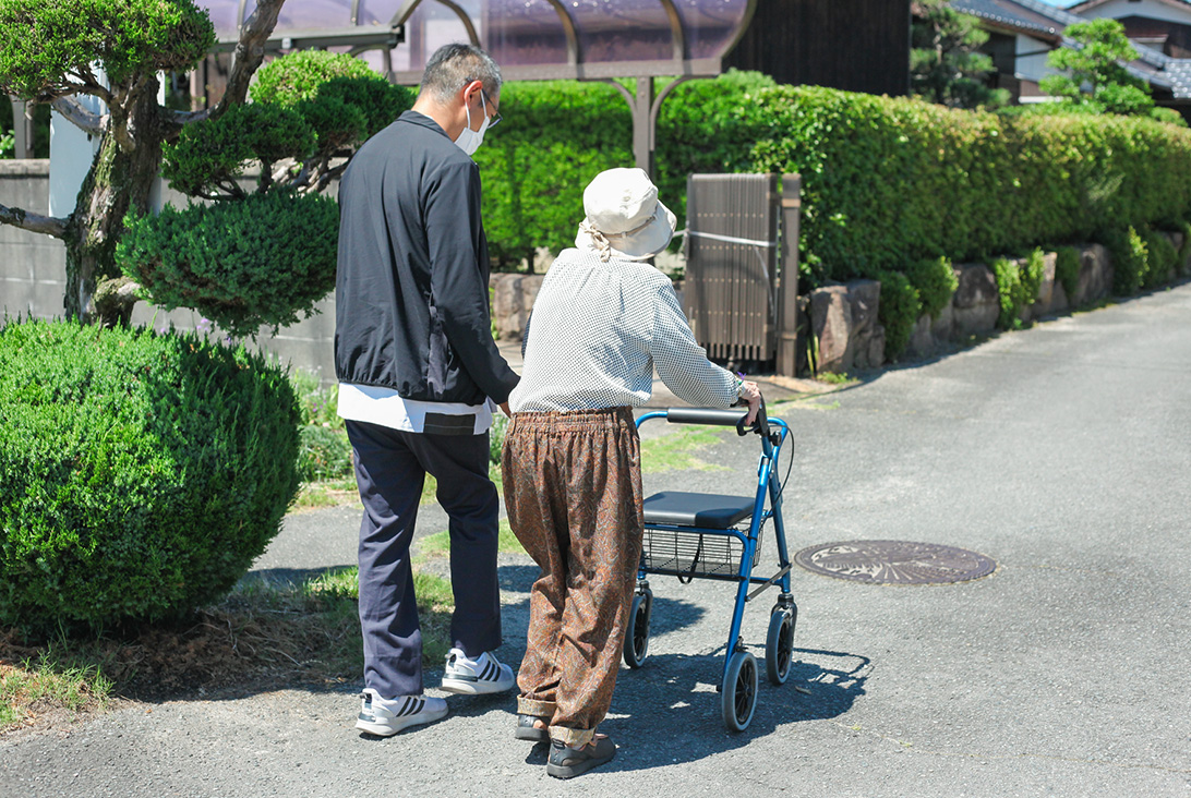 画像：リハビリスタッフと歩行の訓練を行う利用者の後ろ姿